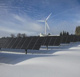 solar panels on snow with windmill under clear day sky